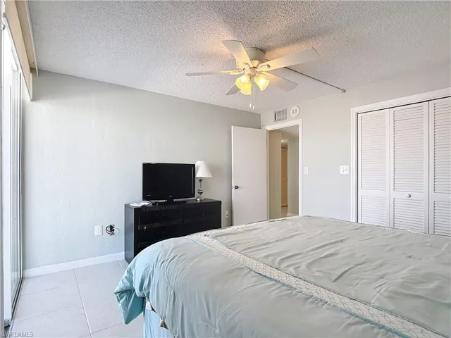 Bedroom with a textured ceiling, a closet, a ceiling fan, and a textured wall