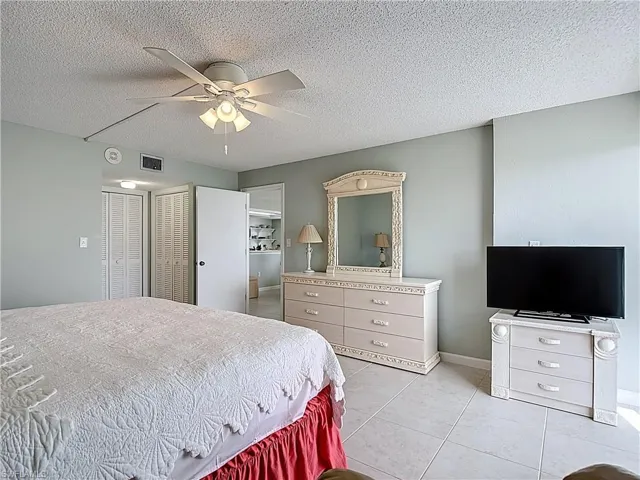 Bedroom with a textured ceiling, a closet, ceiling fan, and light tile patterned floors