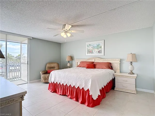 Bedroom featuring a textured ceiling, access to outside, light tile patterned floors, and ceiling fan