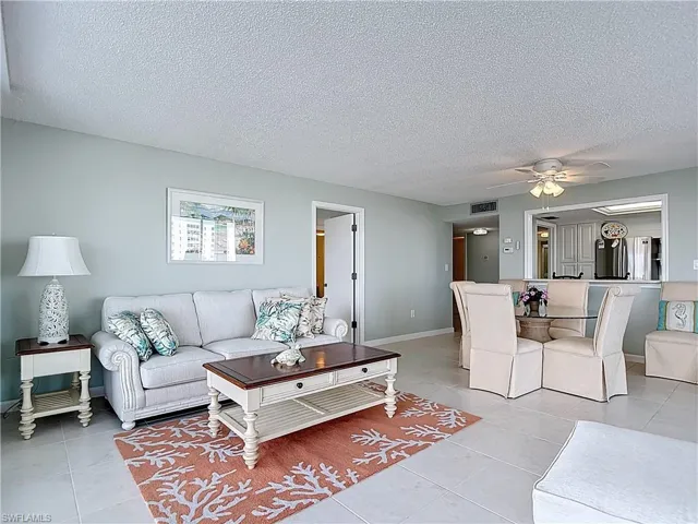 Living room featuring a textured ceiling, a ceiling fan, and light tile patterned floors