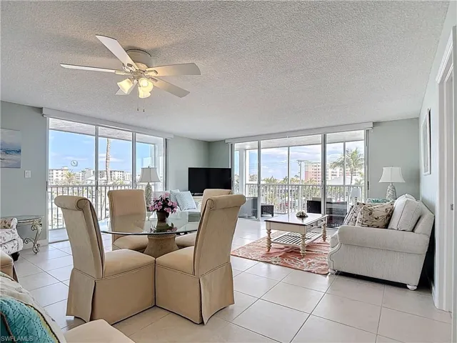 Dining space featuring floor to ceiling windows, light tile patterned floors, a textured ceiling, and a ceiling fan