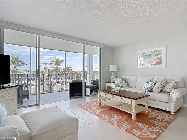 Living room featuring floor to ceiling windows, plenty of natural light, a textured ceiling, and light tile patterned flooring