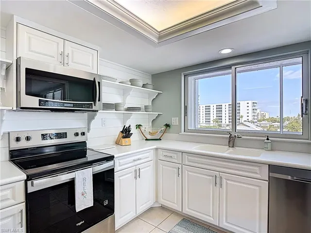 Kitchen featuring stainless steel appliances, white cabinetry, open shelves, and light tile patterned floors