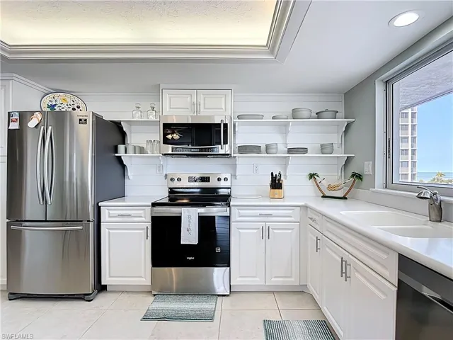 Kitchen featuring stainless steel appliances, white cabinets, open shelves, and light tile patterned floors