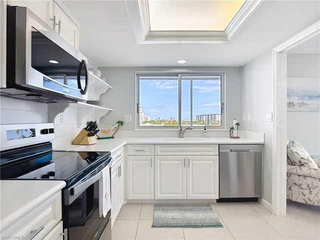 Kitchen featuring stainless steel appliances, white cabinetry, light tile patterned flooring, and open shelves