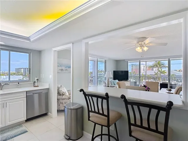 Kitchen featuring dishwasher, light countertops, healthy amount of natural light, and white cabinets