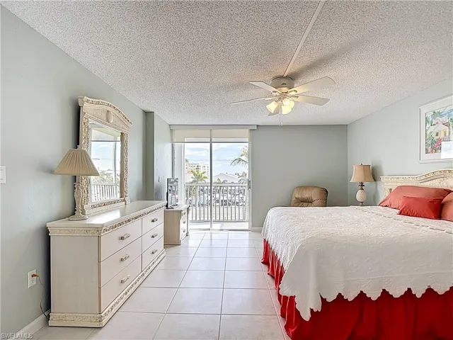Bedroom with access to exterior, a textured ceiling, light tile patterned floors, and a ceiling fan