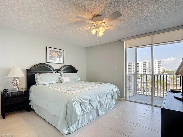 Bedroom with floor to ceiling windows, a textured ceiling, access to exterior, light tile patterned floors, and a ceiling fan