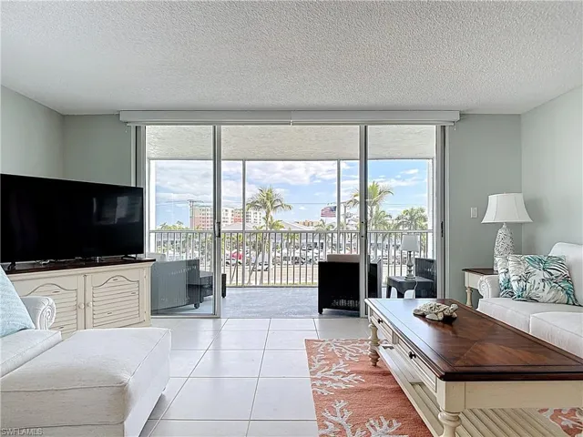 Living room with floor to ceiling windows, light tile patterned flooring, and a textured ceiling
