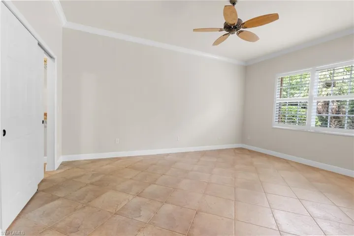Primary Bedroom tiled throughout with windows onto preserve and walk-in closet.