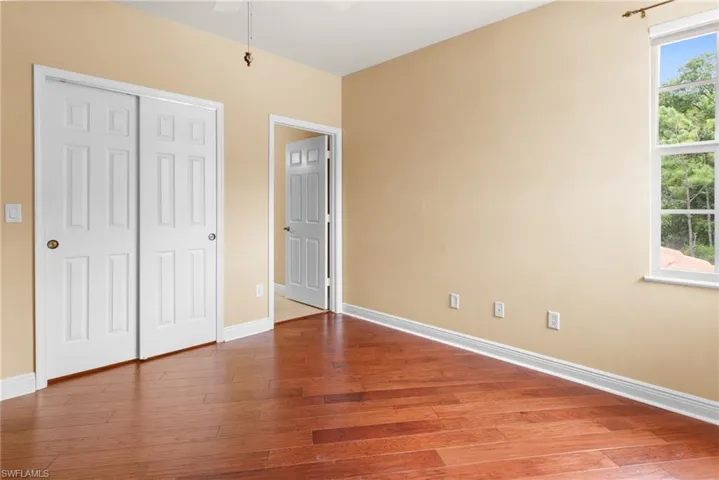 Guest bedroom 1 featuring ceiling fan, wood flooring and walk-n closet.
