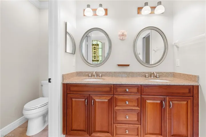 Bathroom featuring double sink vanity, toilet, and tile floors.