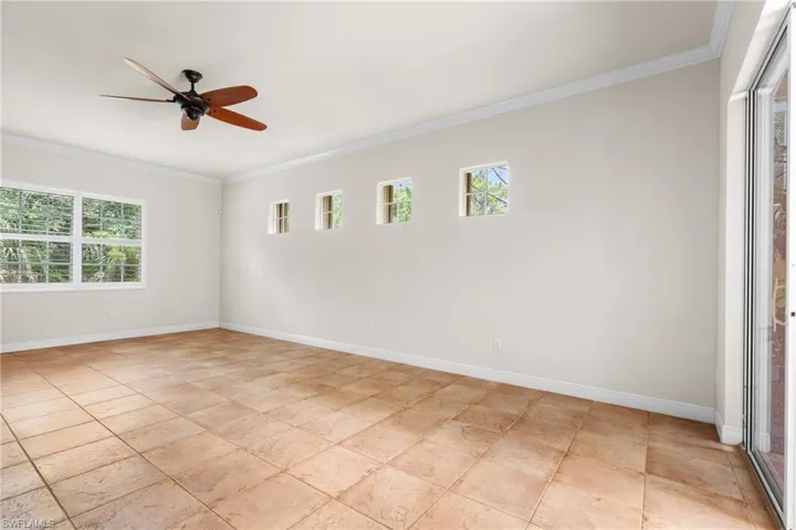 Great Room living with tiled flooring, crown molding, windows onto preserve area.