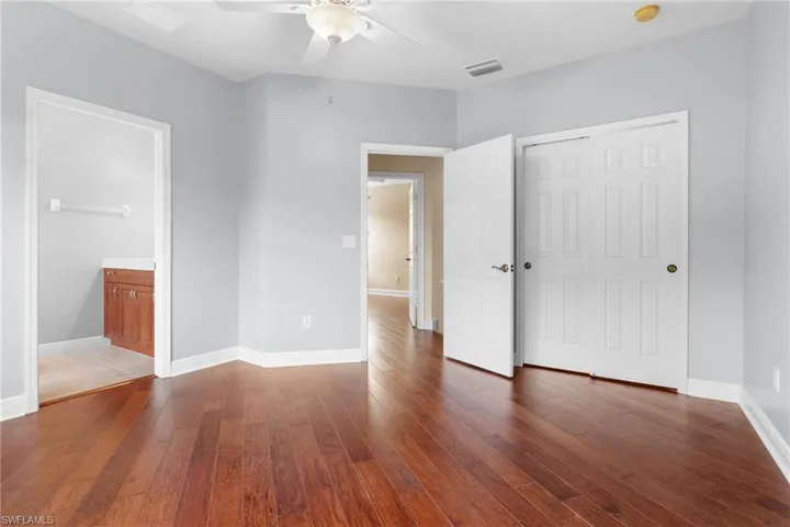 Guest bedroom 2 featuring a walk-in closet, wood flooring, and ceiling fan. Bath ensuite.