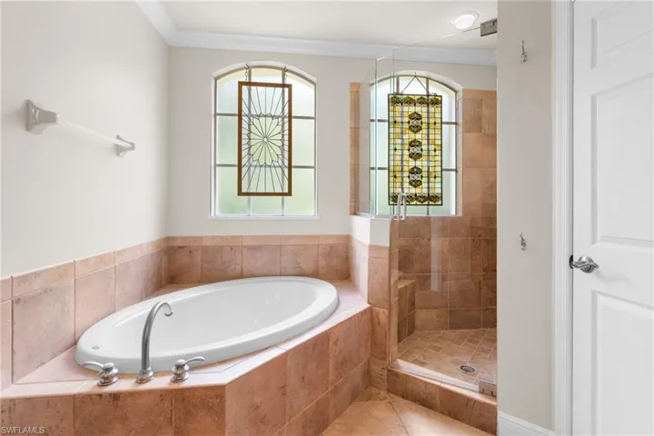 Bathroom with glass window artwork, soaking tub & walk-in shower.