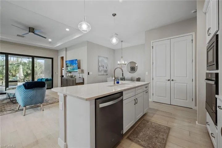 Kitchen featuring stainless steel dishwasher, open floor plan, white cabinetry, a sink, and built in microwave