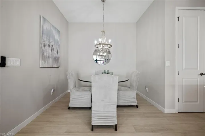 Dining area with light wood-style flooring, baseboards, and an inviting chandelier