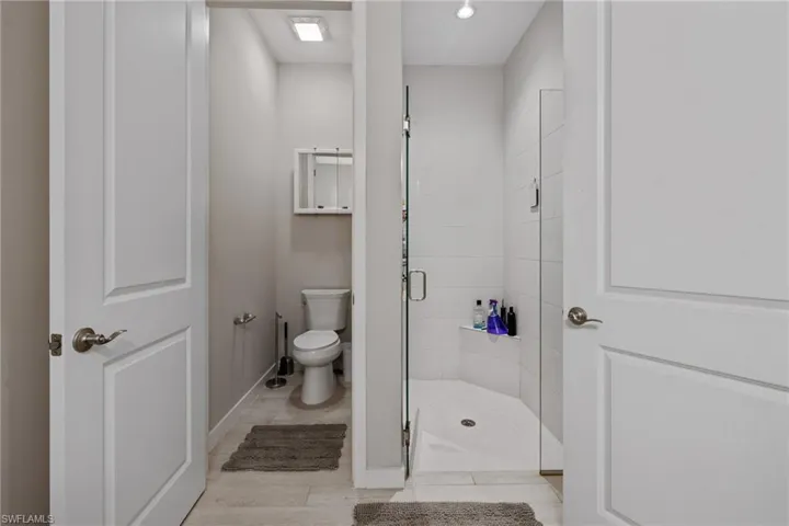 Bathroom with a stall shower, toilet, and baseboards