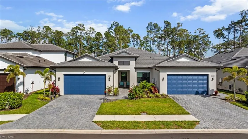 View of front of property featuring a garage, a tile roof, decorative driveway, and stucco siding