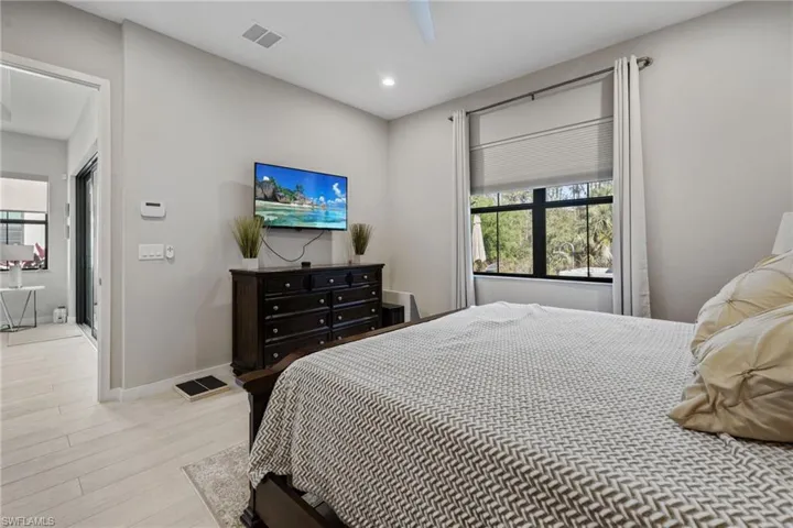 Bedroom with light wood finished floors, baseboards, visible vents, and recessed lighting