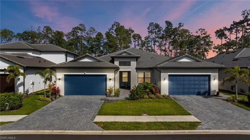 View of front facade with a garage, stucco siding, decorative driveway, and a tiled roof