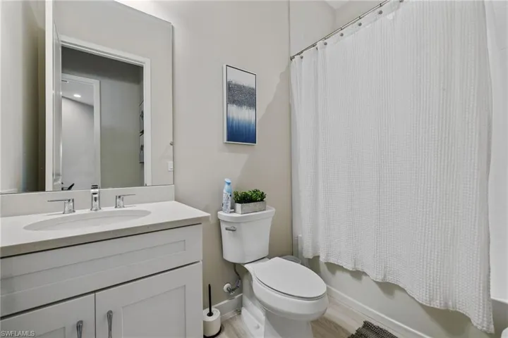 Full bathroom featuring toilet, shower / tub combo, wood finished floors, visible vents, and vanity