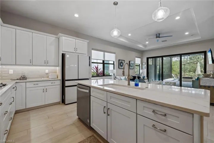 Kitchen featuring a sink, white cabinets, freestanding refrigerator, dishwasher, and a raised ceiling