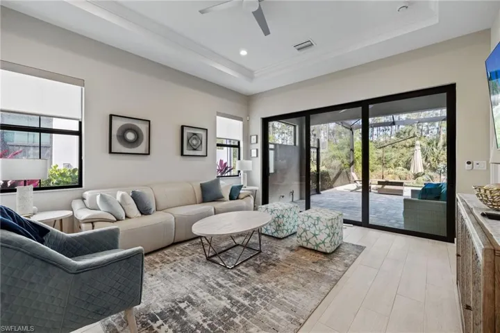 Living room featuring light wood finished floors, visible vents, a raised ceiling, and recessed lighting