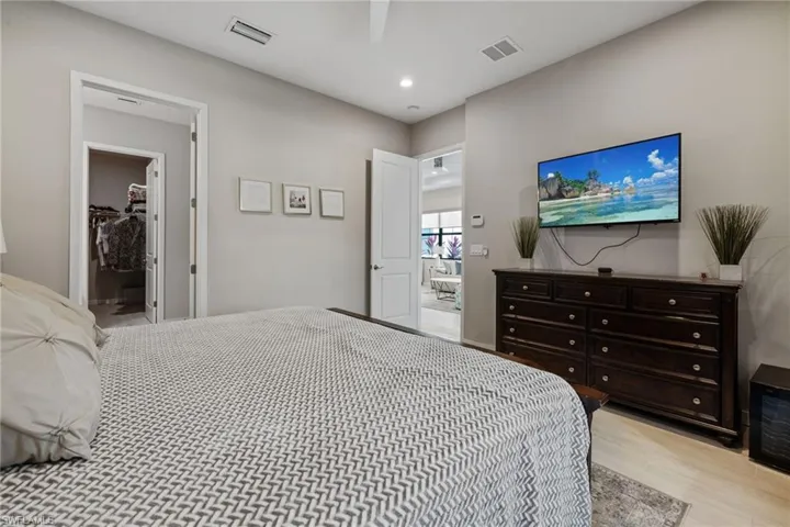 Bedroom with light wood finished floors, visible vents, a walk in closet, and recessed lighting