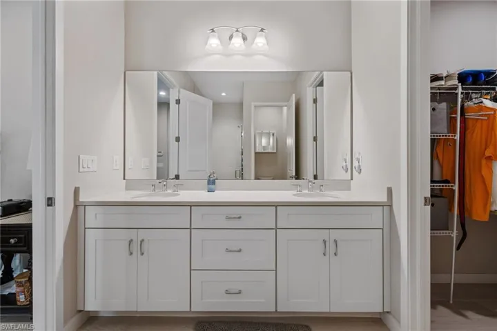 Bathroom with a spacious closet, double vanity, a sink, and baseboards