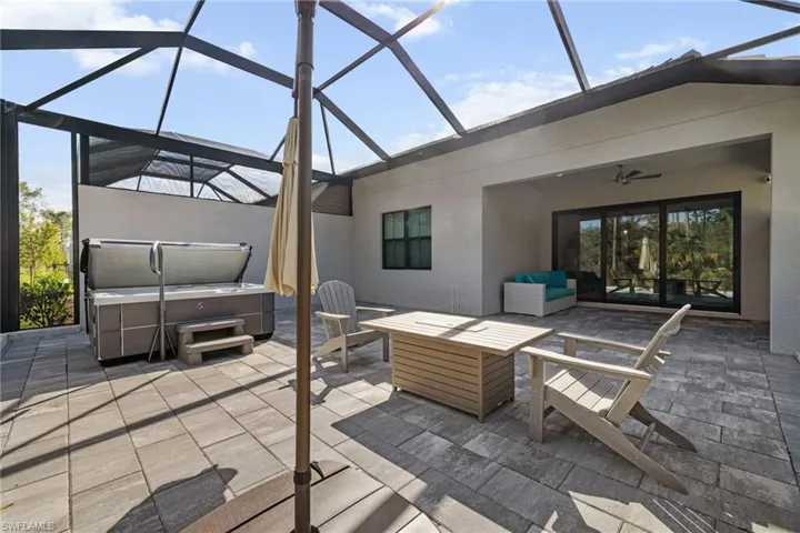 View of patio / terrace with a lanai, ceiling fan, a hot tub, and an outdoor living space