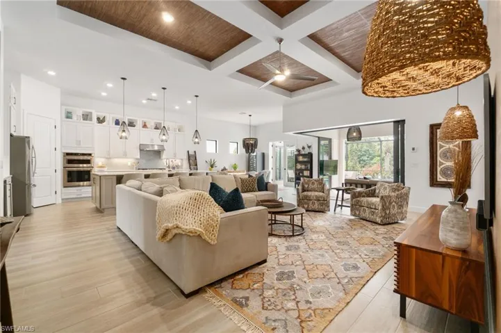 The coffered ceiling in the living room has been beautifully enhanced with real wood wallpaper and complemented by elegant hanging lights