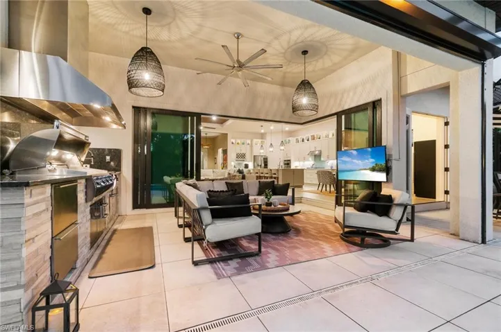 The outdoor kitchen features a built-in 48" FireMagic grill, side burner, two-drawer refrigerator, and sink
