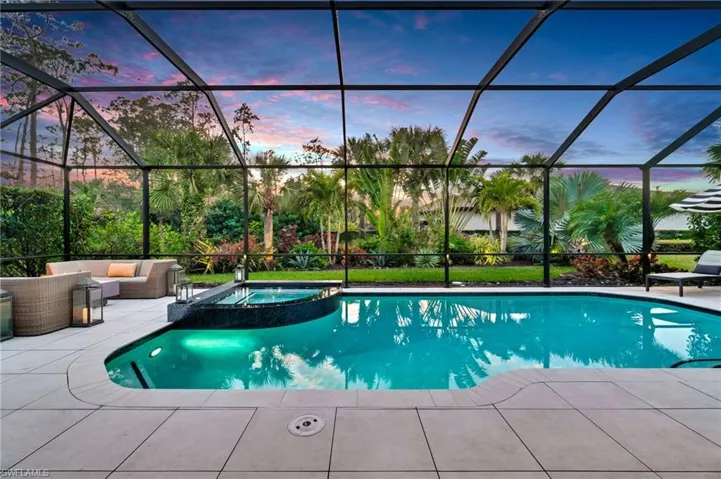 Dusk poolside retreat with an in-ground hot tub, outdoor lounge, patio, and screened lanai