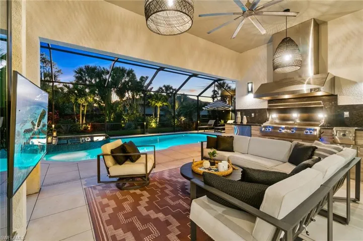 The outdoor kitchen features a built-in 48" FireMagic grill, side burner, two-drawer refrigerator, and sink