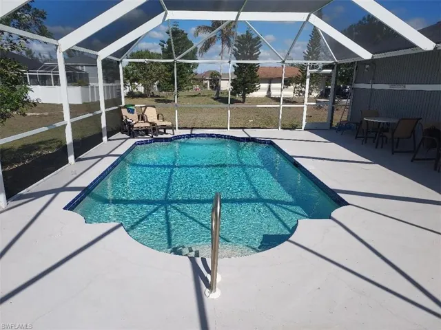 Screened swimming pool with a curved entry, surrounded by a concrete deck and a white aluminum enclosure