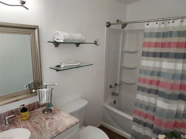 Bathroom featuring a single vanity with a patterned countertop, a white basin, and a framed mirror