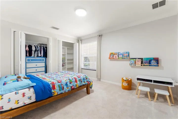 Carpeted bedroom featuring crown molding and multiple closets