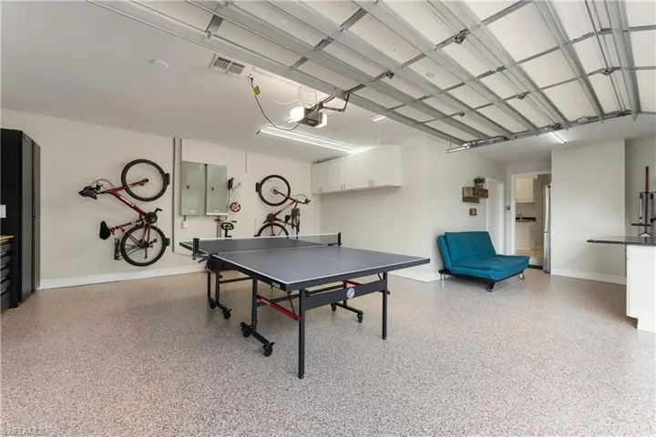 Recreation room with electric panel, a garage, and dark aggregate flooring