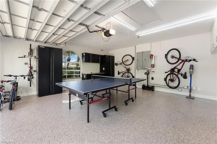 Game room featuring a garage, dark aggregate flooring, attic access, and electric panel
