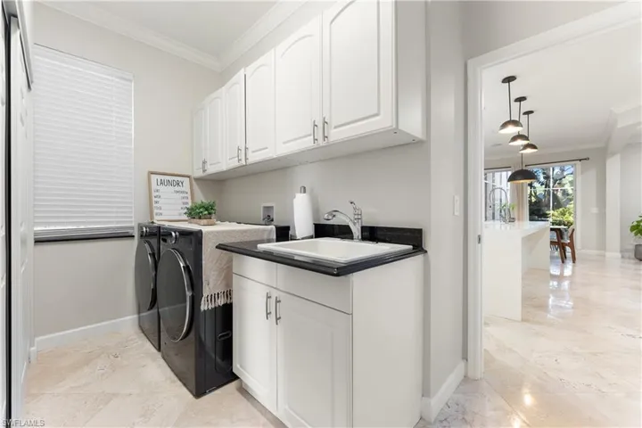 Washroom with ornamental molding, cabinet space, and washing machine and clothes dryer