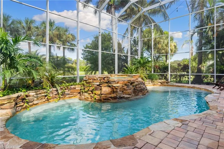 View of pool featuring a lanai, a pool with connected hot tub, and a sunroom