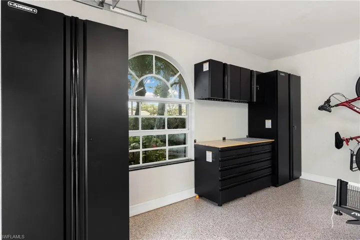 Kitchen featuring dark cabinets, light countertops, freestanding refrigerator, dark speckled floor, and a textured wall