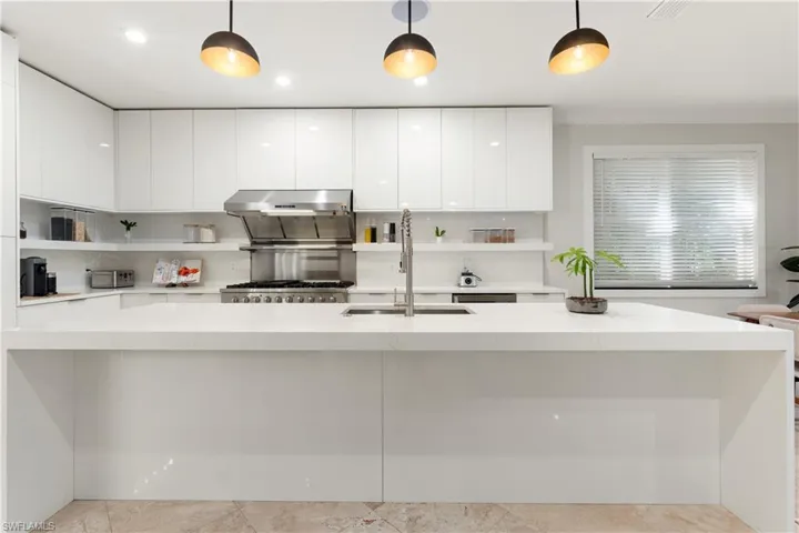 Kitchen featuring open shelves, modern cabinets, a large island, and light stone counters
