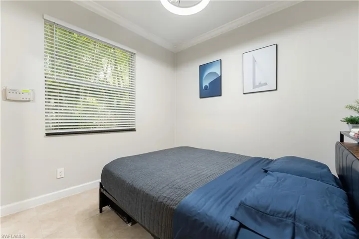 Tiled bedroom featuring crown molding and baseboards