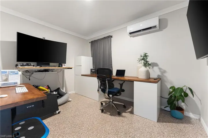 Office featuring crown molding, a wall mounted air conditioner, and dark aggregate flooring