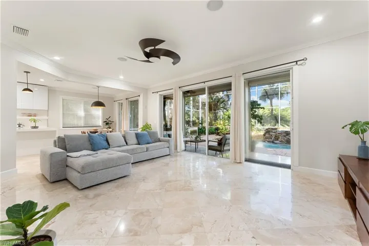 Living room featuring ornamental molding, recessed lighting, ceiling fan, and light marble finish floors