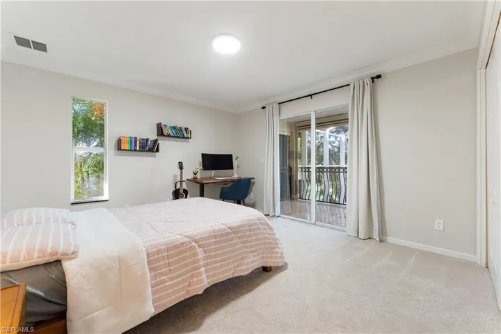 Carpeted bedroom with ornamental molding, an office area, and access to exterior