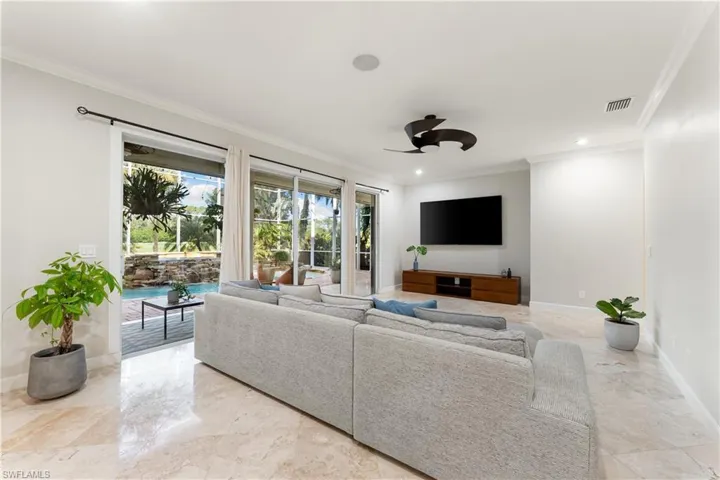Living area featuring ornamental molding, a ceiling fan, recessed lighting, and light marble finish flooring