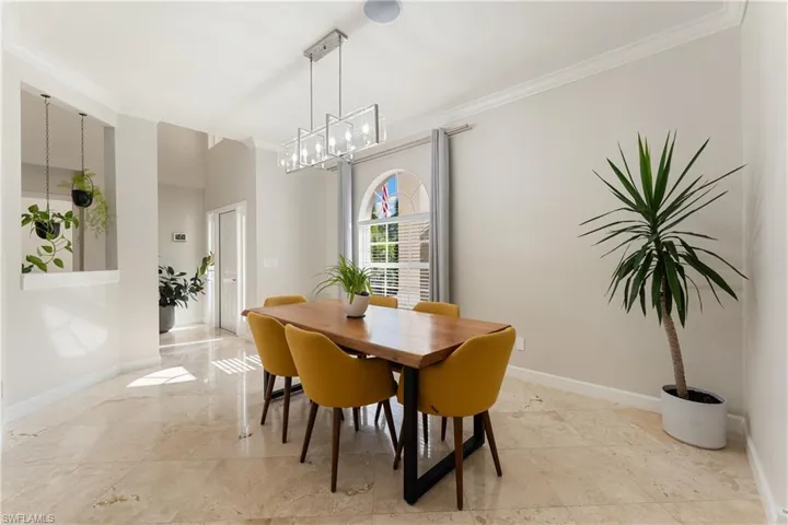 Dining room featuring ornamental molding and light marble finish floors